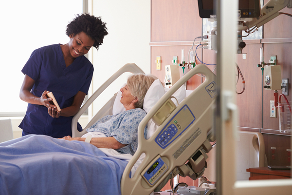 Image of a senior female patient in a hospital bed speaking with her nurse about her plan of care