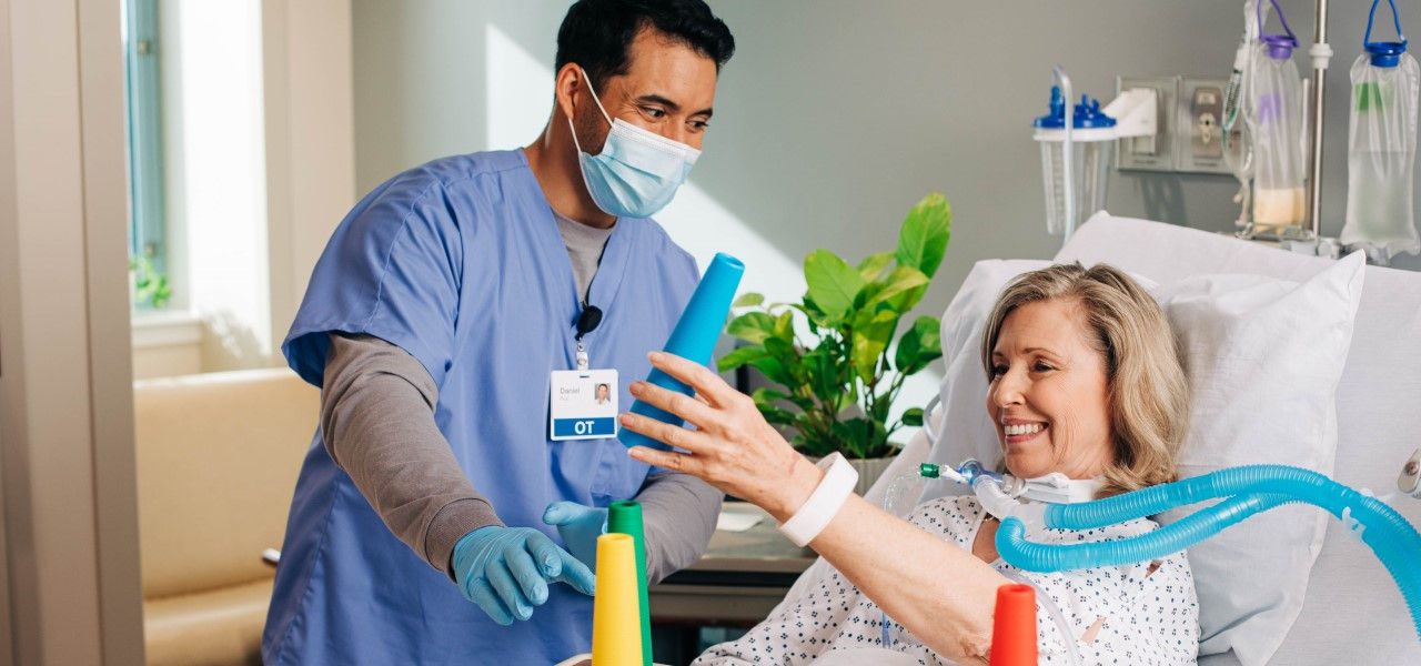 Caregiver helping happy patient with rehab exercise