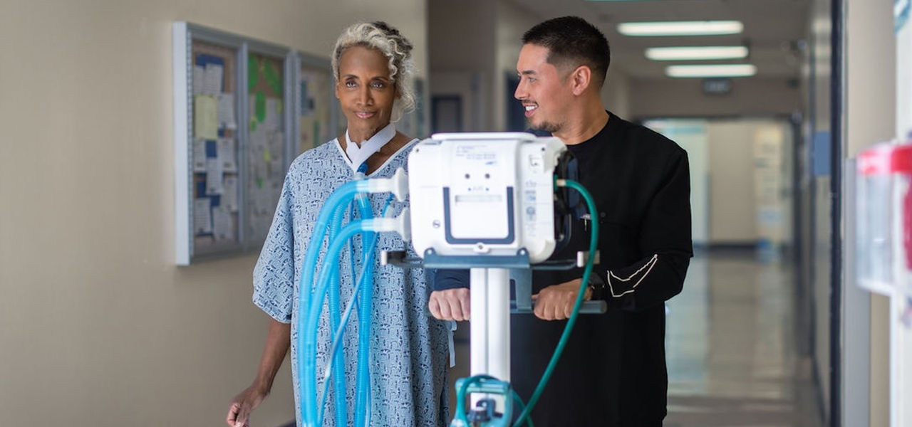 Improving Outcomes Image Female patient walking down hallway