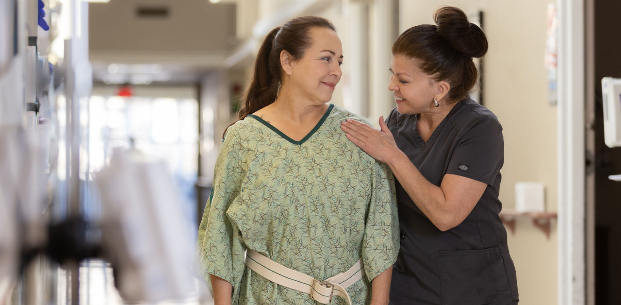 happy nurse helping a patient walk in hall
