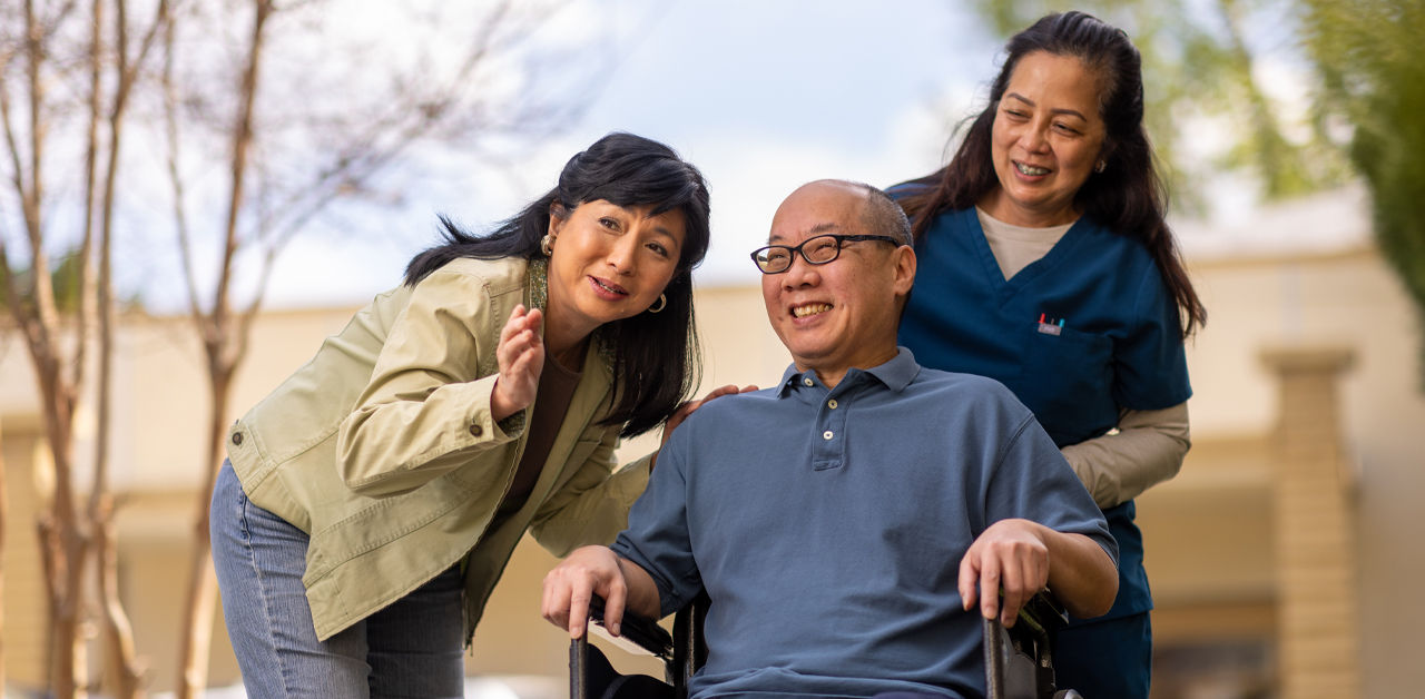 husband in wheelchair with wife and caregiver
