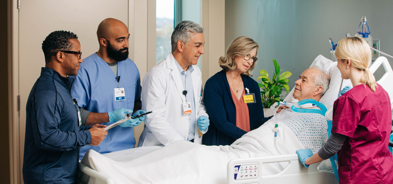 Medical professionals surround a patient in a hospital bed