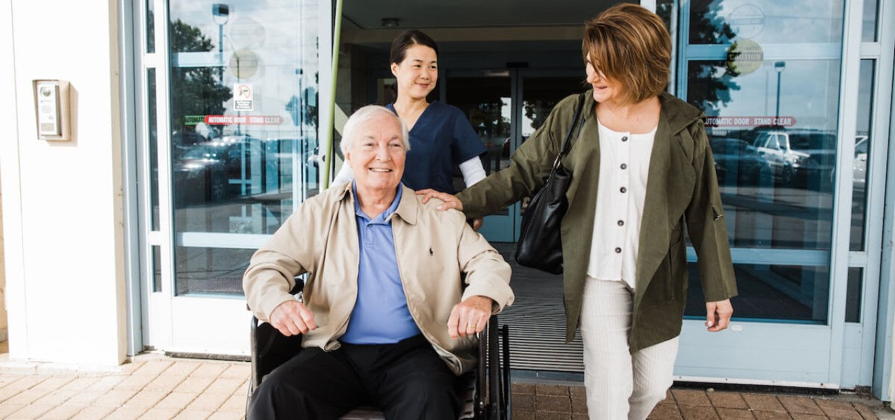 Happy patient in wheelchair exiting the hospital