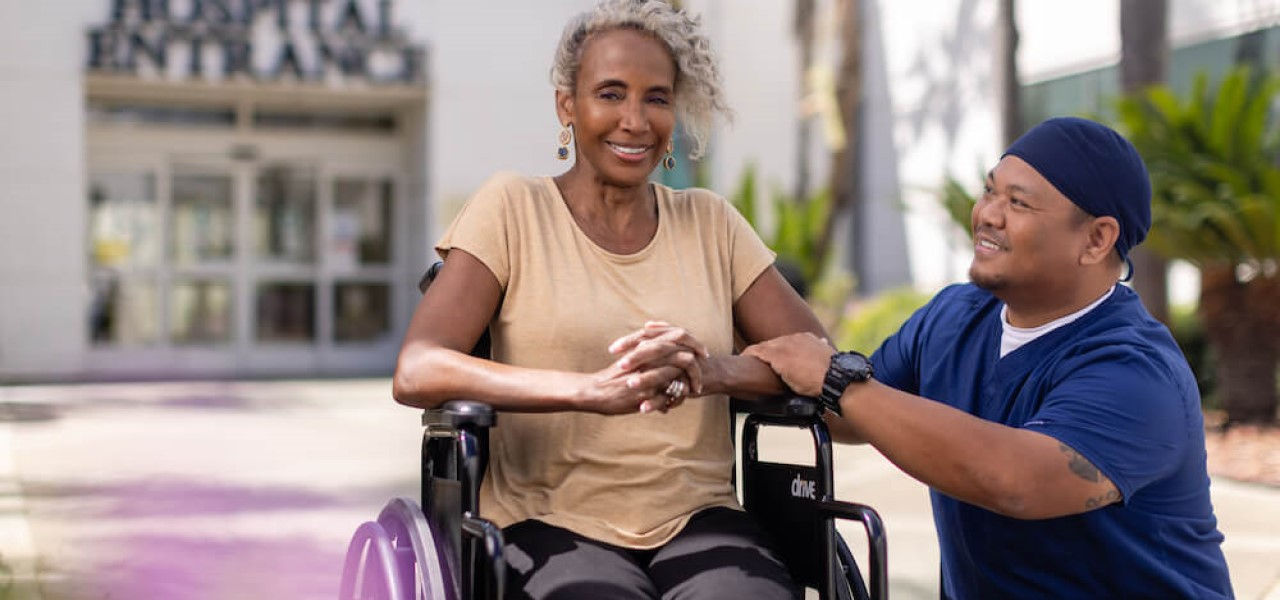 Happy patient in wheelchair talking to a nurse