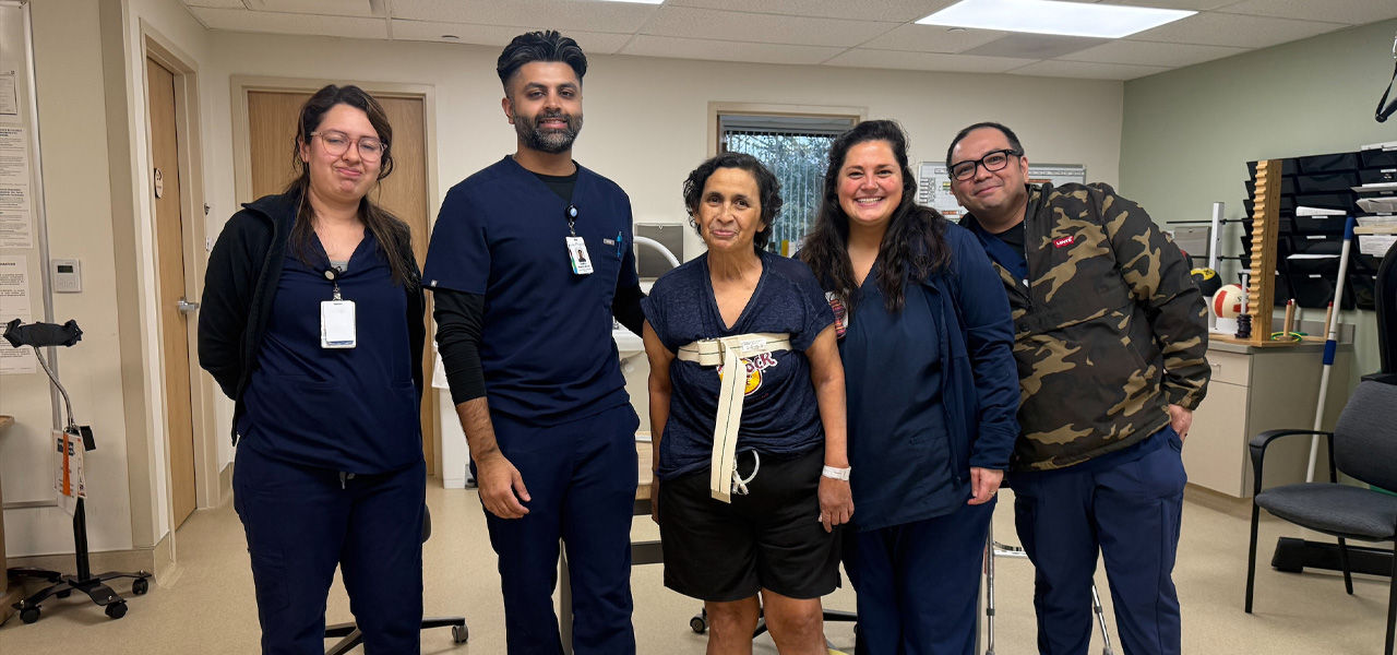 Anna patient at Kindred Hospital Sugarland stands with her support staff 