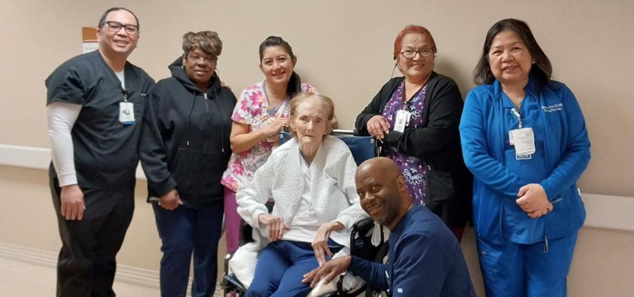 Delores patient at Kindred Hospital Sugar Land poses with her support team of nurses and caregivers