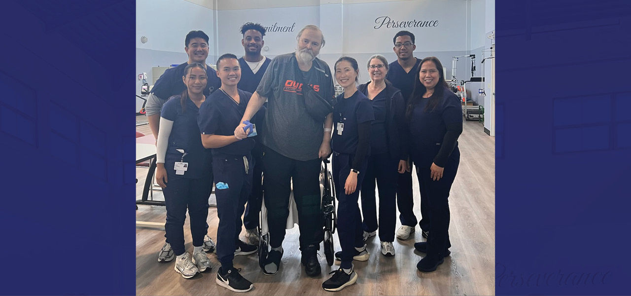 Kindred Hospital Brea patient Gregory stands and poses with his care team in the rehab gym