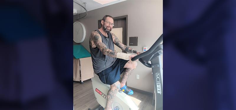 Kindred Hospital Denver patient Michael poses on exercise bike while telling his story of successful recovery from respiratory condition